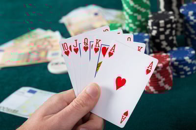 Mans hand holding royal flush in poker game
